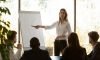 Female business coach speaker pointing on flip chart presenting work results graph at conference office meeting, businesswoman mentor presenter training staff group at corporate workshop presentation Female speaker give flip chart presentation at conference training meeting